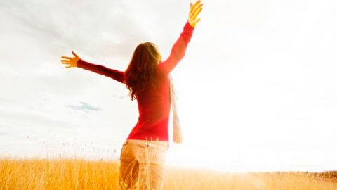 Young girl spreading hands with joy and inspiration facing the sun